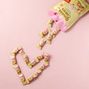 Individual lychee Prince of Peace Ginger Chew pieces arranged to form a heart on a pink background.