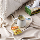 A cup of Prince of Peace Instant Turmeric Ginger Honey Crystals in a cup with a pillow aside on a blanket.