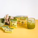 A glass ofPrince of Peace Ginger Honey Crystals Matcha cold drink with sachets and gingers on a table.