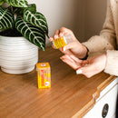 A lady is taking some pills from a bottle of Trumpet Brand Seirogan TOI-A and a box on the table with a planet aside.