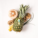 A piece of Prince of Peace Ginger Candy (Chews) Pineapple Coconut on a pineapple with ginger and a coconut on a white background.