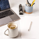 A cup of Ginger hot drink with a laptop, a pen, papers and a pen holder around.