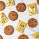 Round-shaped biscuits with Prince of Peace Instant Ginger Honey Crystals sachets on a white background.