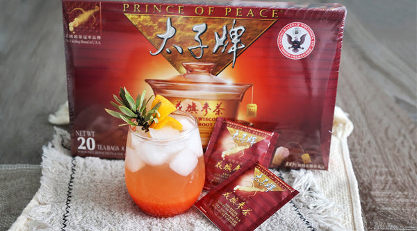 A glass of American Ginseng Guava Orange drink with a box of Prince of Peace American Root Tea.