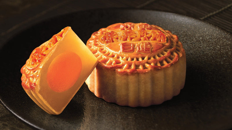 One and a cube of Wing Wah 2 Yolks White Lotus Seed Paste Mooncake on a plate.