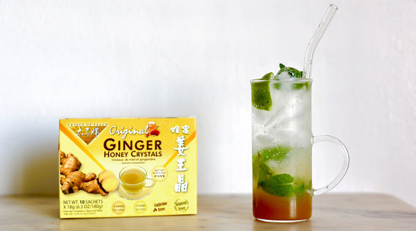 A box of Prince of Peace Ginger Honey Crystal with a glass of Ginger Lime Mint Sparkling Water