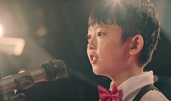 A young boy on stage with a microphone.