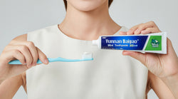 A lady hold a YNBY toothpaste and a tooth brush.