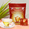 A glass of Prince of Peace Wisconsin American Ginseng Root Tea with a package and 2 tea bags on a table.