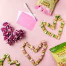 Ginger Chew Lychee and Ginger Chew Mango with chews line as heart shapes on a pink background.