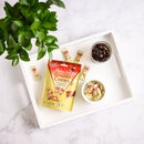 A package of Ginger Chews Cola on a white tray with a plant in the background