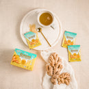 Ginger Honey Crystal Yuze packets with a cup of tea and cookies on a beige surface