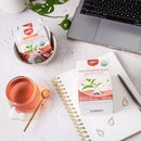 Tea packaging, cup of tea, and laptop on a desk