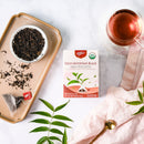A package of Prince of Peace High Mountain Black Organic Whole Leaf Tea with a cup of tea and tea leaves aside.
