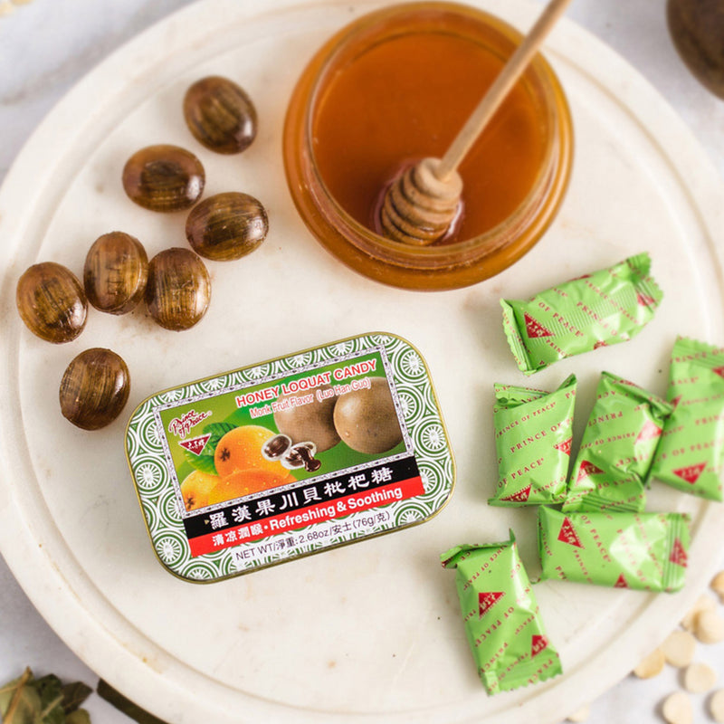 Some Prince of Peace Honey Loquat Candy Monk Fruit Flavor with a honey jar on a plate.
