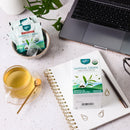 A package of Prince of Peace Imperial Green Organic Whole Leaf Tea with a cup of tea, tea bags and a laptop aside.
