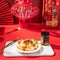 On Kee XO Sauce with Whole Abalone on noodles in a plate with a package aside on a red background.