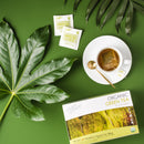 Prince of Peace Organic Green Tea in a cup with a package, tea bags and tree leaves aside on a green background.
