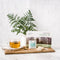 Prince of Peace Organic Oolong Tea in a glass on a wooden tray with a package and tea bags in front of a vase.