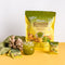 A glass of cold Prince of Peace Ginger Honey Crystals with Matcha with sachets, gingers and package on a able.