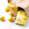 A package of Prince of Peace Ginger Candy (Chews) with Lemon and a box of Ginger Honey Crystal with some lemons and ginger in a paper bag on a white background.