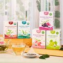 A bright, lifestyle product photograph featuring five Prince of Peace Whole Leaf Tea boxes arranged on a light wooden table and tiered riser set against a soft blurred background with leaves.
