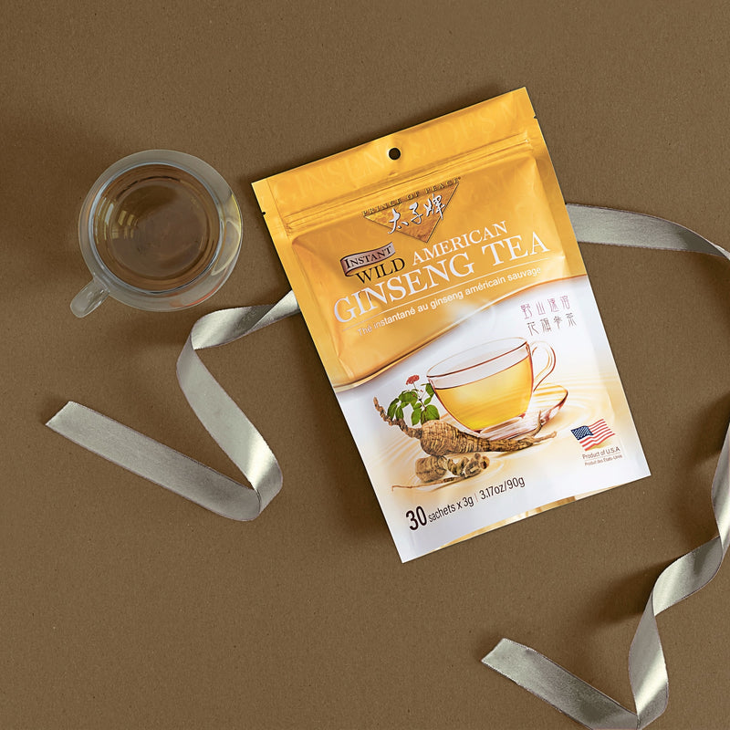A glass of Prince of Peace Instant Wild American Ginseng Tea bag with a ribbon and package. 