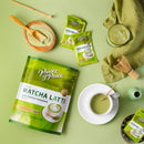 A glass of cold Prince of Peace 3-in-1 Instant Matcha Latte and a cup of hot one with matcha powder and sachets aside.