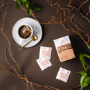 A cup of Prince of Peace Organic Black Tea with a package teabags, and treebeard around on a brown background.