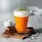 A glass of Prince of Peace 3-in-1  Thai Tea with chocolate cookies on a wooden tray and ice cubes around.