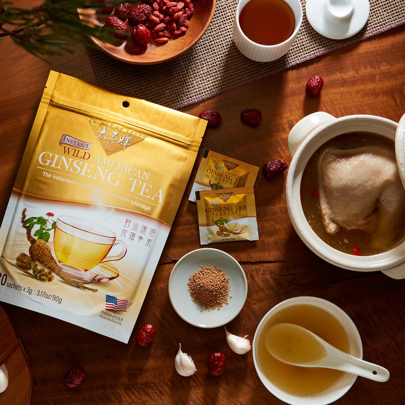 Prince of Peace Instant Wild American Ginseng Tea bag, sachet, powder and a pot of chichen soup on a table.